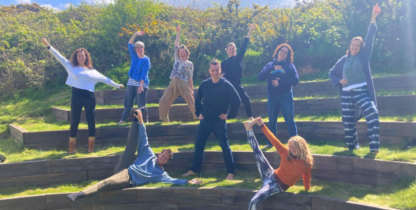 A group of happy people standing and lounging on steps. Some have their hands in the air in a jubilant way.