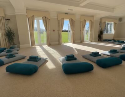 Large room with triple set of three french doors, cream carpet set up for yoga lesson with comfortable mats and bricks.