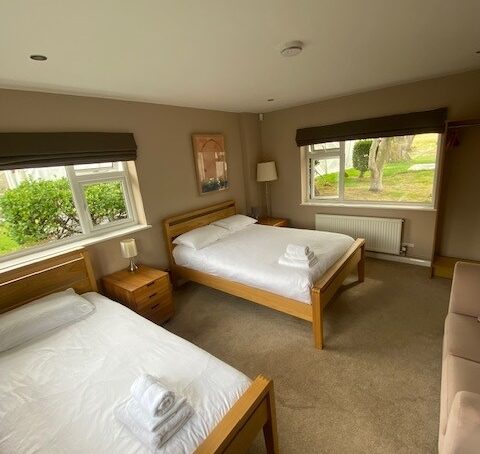 Two double wooden framed beds with white bedding and towels. Blinds on two winds are raised and nice views of the garden